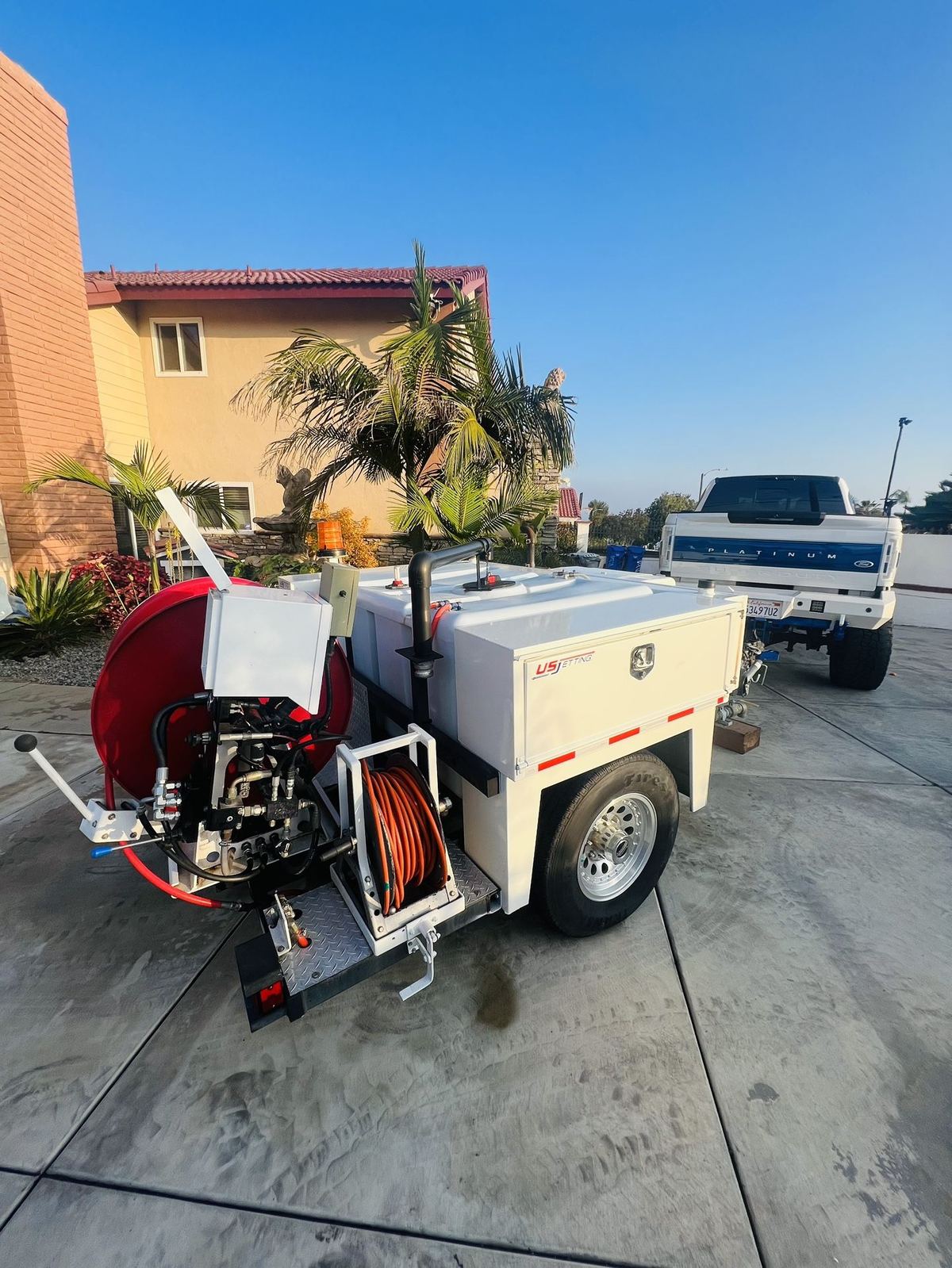 Viper's US Jetting trailer-mounted hydro jetter hitched to a service truck on a residential job